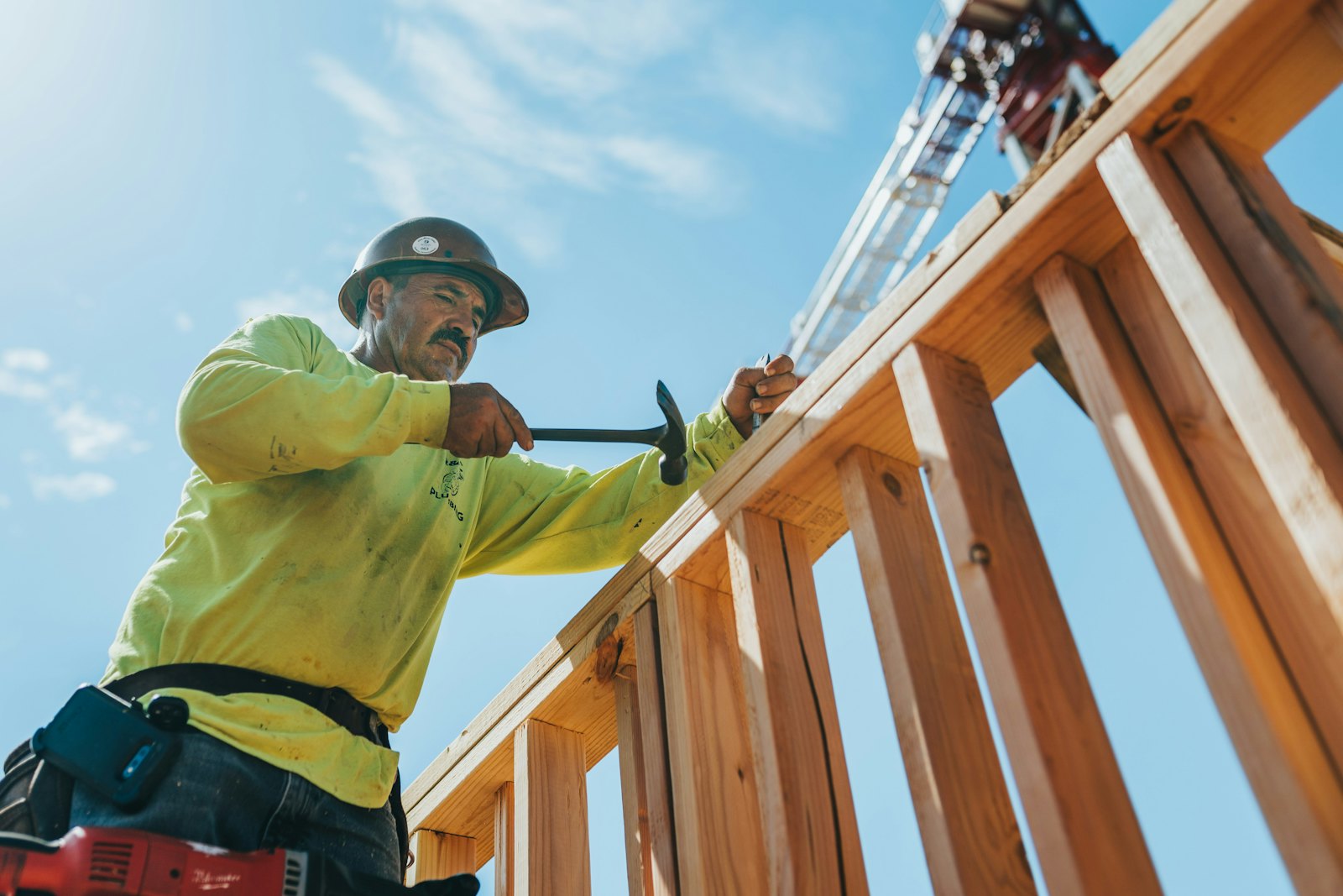 A carpenter in a hard hat working on a new wood frame
